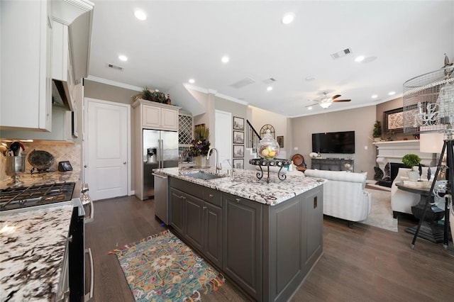 kitchen with tasteful backsplash, an island with sink, sink, white cabinets, and stainless steel appliances