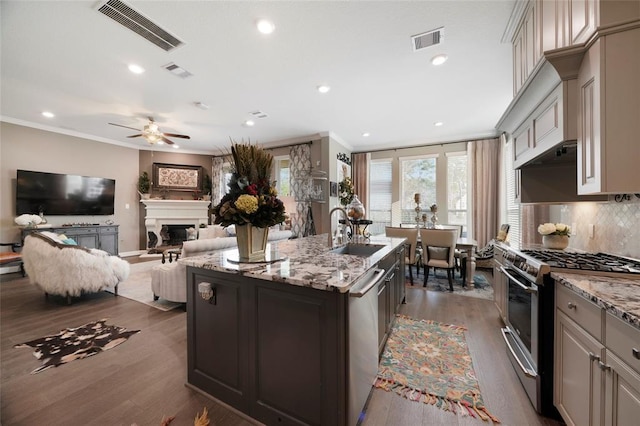 kitchen featuring sink, ornamental molding, stainless steel appliances, and an island with sink