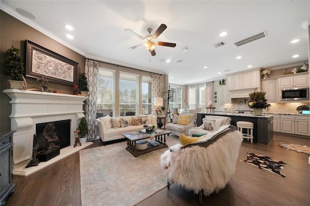 living room featuring crown molding, ceiling fan, and dark hardwood / wood-style floors