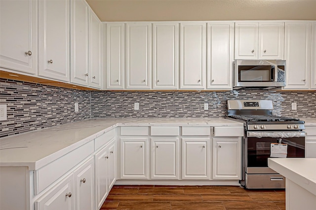 kitchen with stainless steel appliances, dark wood-type flooring, white cabinets, and decorative backsplash