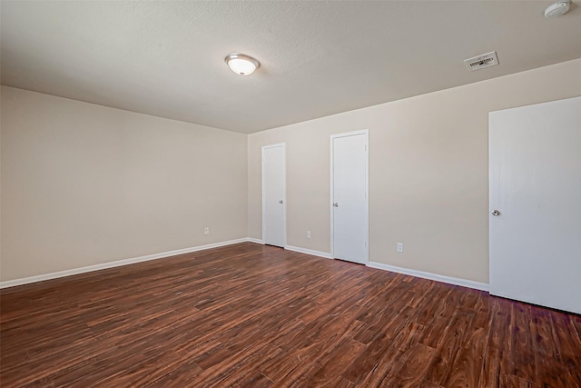 spare room featuring a textured ceiling and dark hardwood / wood-style flooring