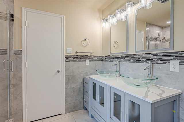 bathroom featuring tile patterned flooring, vanity, a shower with shower door, and tile walls