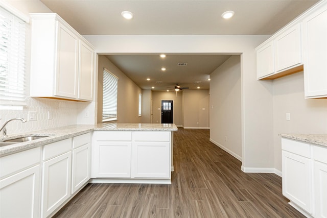 kitchen with sink, white cabinets, dark hardwood / wood-style flooring, kitchen peninsula, and light stone countertops