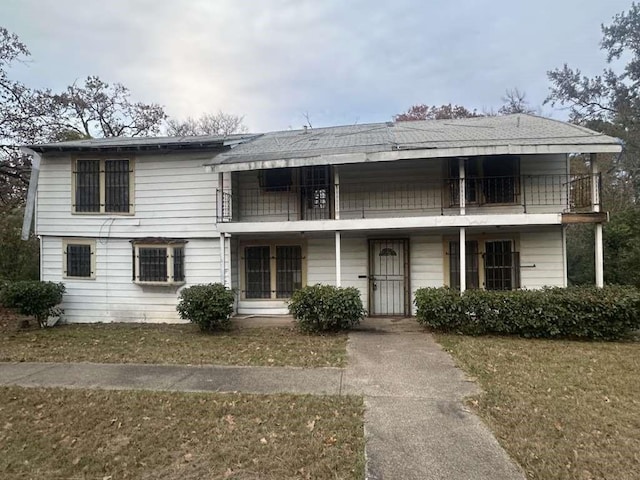 view of front of house featuring a balcony and a front yard