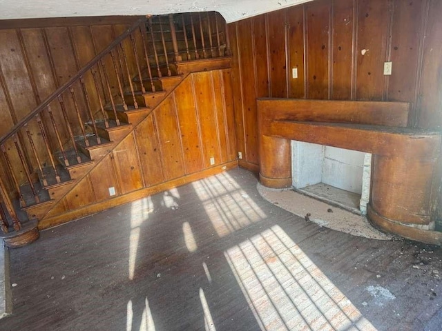 unfurnished living room featuring a fireplace, light hardwood / wood-style flooring, and wood walls