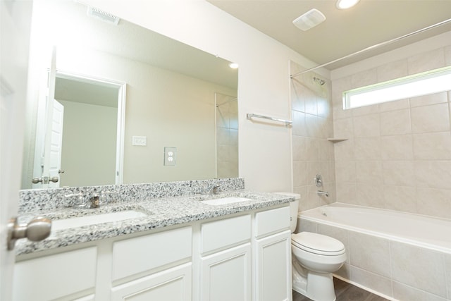 full bathroom featuring hardwood / wood-style flooring, tiled shower / bath, vanity, and toilet