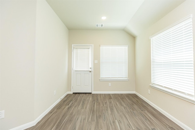 spare room with wood-type flooring and lofted ceiling