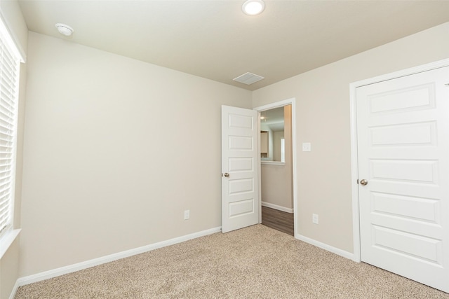 unfurnished bedroom with light colored carpet and a closet