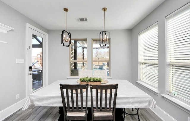 dining space featuring wood-type flooring, a chandelier, and plenty of natural light