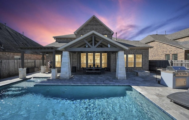 back house at dusk with area for grilling and a patio area