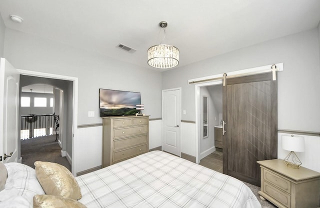 bedroom featuring a barn door and a chandelier