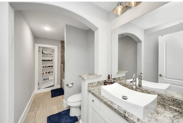 bathroom featuring vanity, wood-type flooring, toilet, and built in shelves