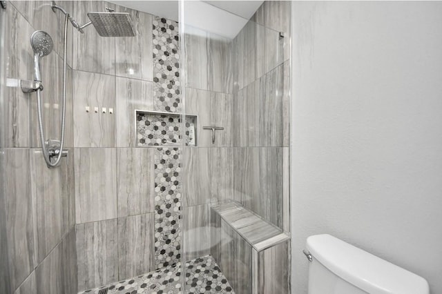 bathroom featuring a tile shower and toilet