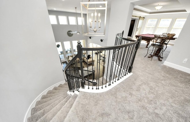 stairway featuring a tray ceiling and carpet