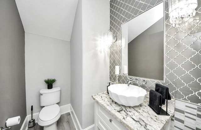 bathroom with vanity, toilet, vaulted ceiling, and wood-type flooring