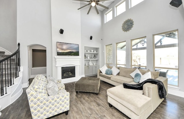 living room featuring a high ceiling, wood-type flooring, a wealth of natural light, and built in features