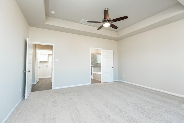 unfurnished bedroom featuring connected bathroom, a tray ceiling, ceiling fan, and carpet