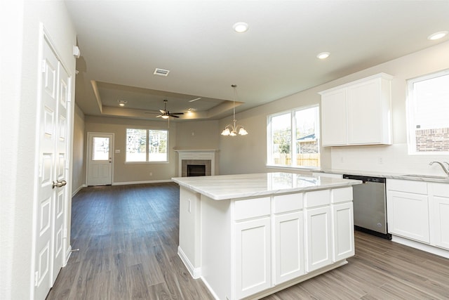 kitchen featuring sink, dishwasher, white cabinetry, a kitchen island, and a raised ceiling