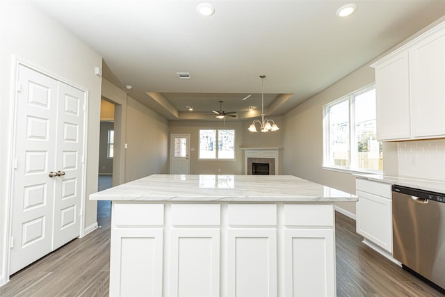 kitchen with a tray ceiling, stainless steel dishwasher, decorative backsplash, and white cabinets