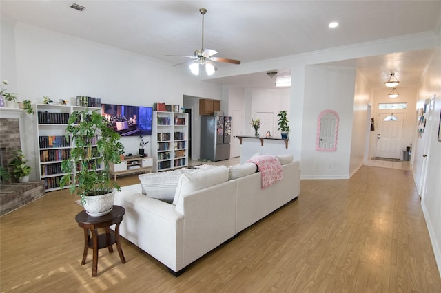 living room featuring a brick fireplace, ornamental molding, light hardwood / wood-style floors, and ceiling fan