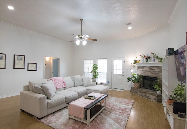 living room featuring hardwood / wood-style floors, crown molding, a fireplace, and ceiling fan