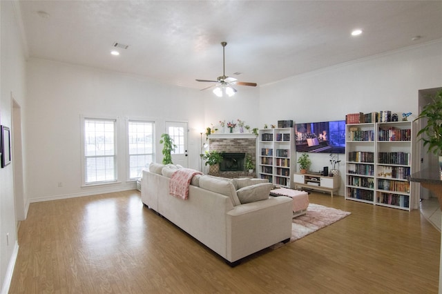 living room featuring a fireplace, crown molding, wood-type flooring, and ceiling fan