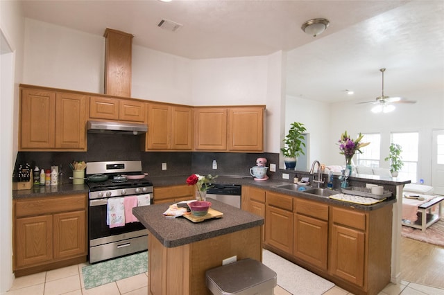 kitchen with sink, a center island, light tile patterned floors, appliances with stainless steel finishes, and kitchen peninsula