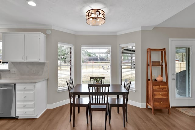 dining area featuring ornamental molding, light hardwood / wood-style floors, and a textured ceiling