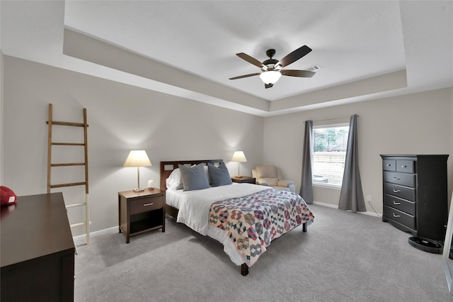 carpeted bedroom featuring a tray ceiling and ceiling fan