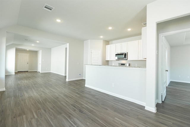 kitchen with white cabinetry, light stone counters, dark hardwood / wood-style flooring, and vaulted ceiling