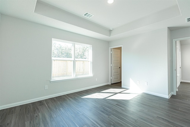 unfurnished room featuring dark wood-type flooring and a raised ceiling