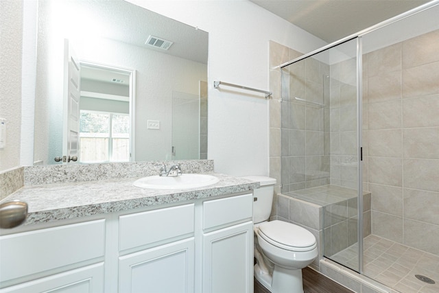 bathroom with an enclosed shower, vanity, hardwood / wood-style flooring, and toilet