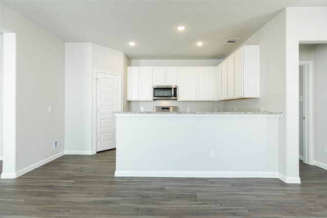 kitchen featuring white cabinetry, light stone countertops, dark hardwood / wood-style floors, and kitchen peninsula