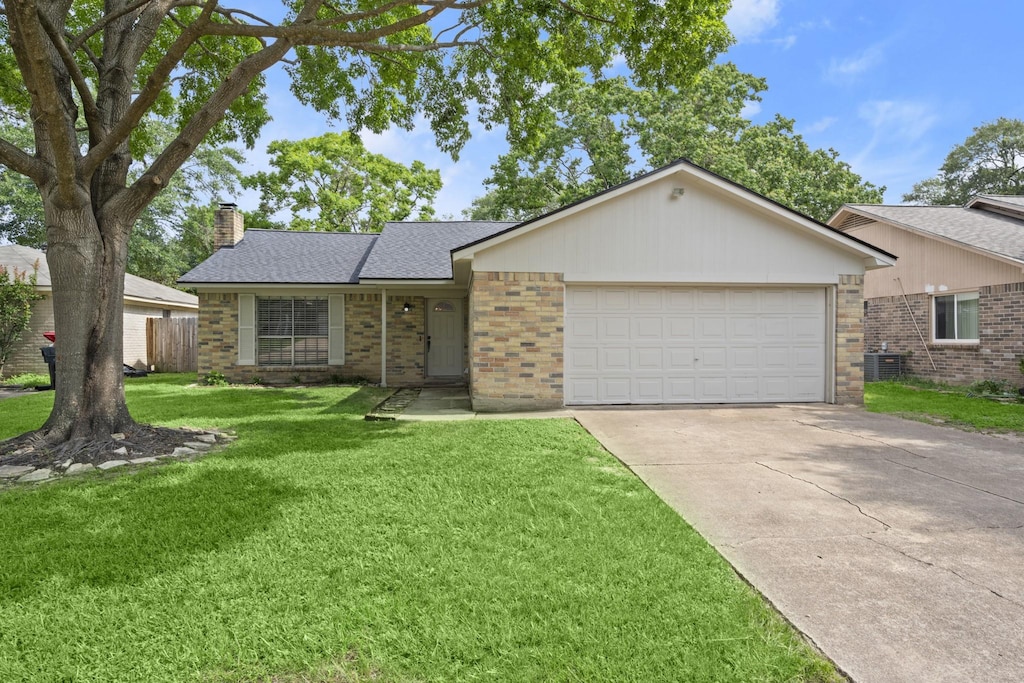 single story home with cooling unit, a garage, and a front yard