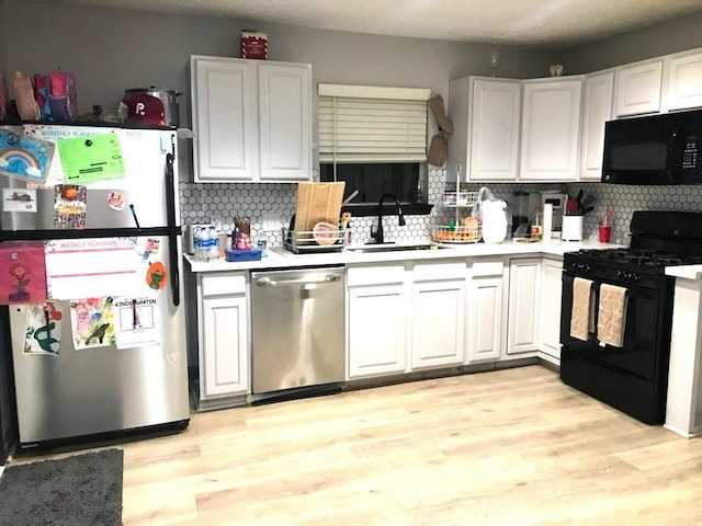 kitchen featuring white cabinetry, light hardwood / wood-style floors, sink, and black appliances