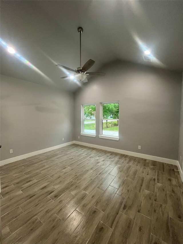 spare room with hardwood / wood-style flooring, vaulted ceiling, and ceiling fan