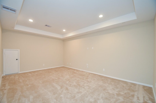 carpeted empty room featuring a tray ceiling