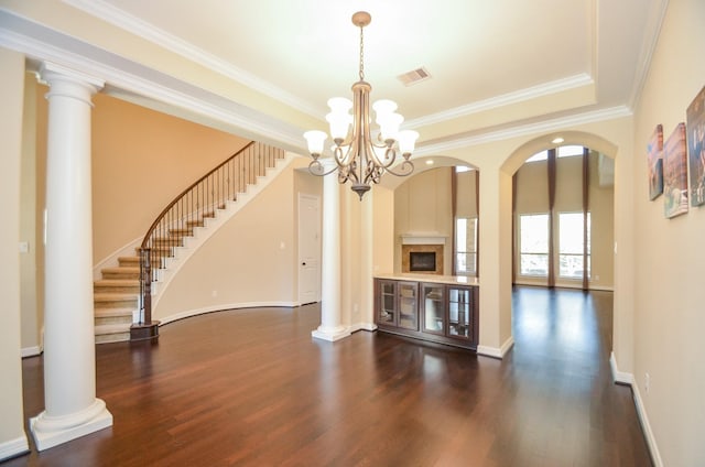 unfurnished living room with ornate columns, ornamental molding, and dark hardwood / wood-style floors