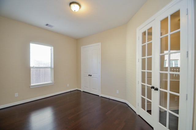 spare room featuring french doors, plenty of natural light, and dark hardwood / wood-style flooring