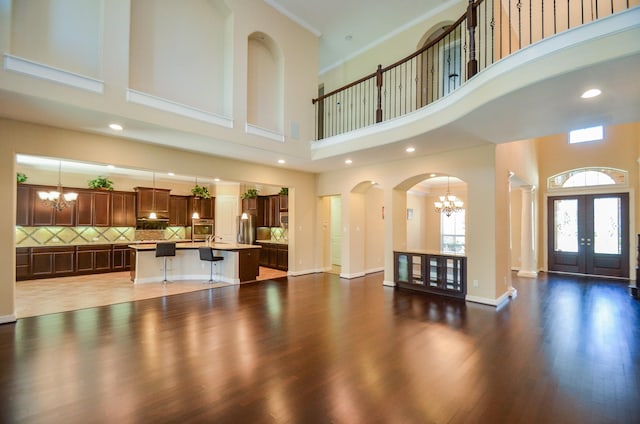 foyer featuring a high ceiling, dark wood-type flooring, a notable chandelier, and french doors