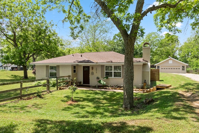 ranch-style house featuring a garage, an outbuilding, and a front lawn