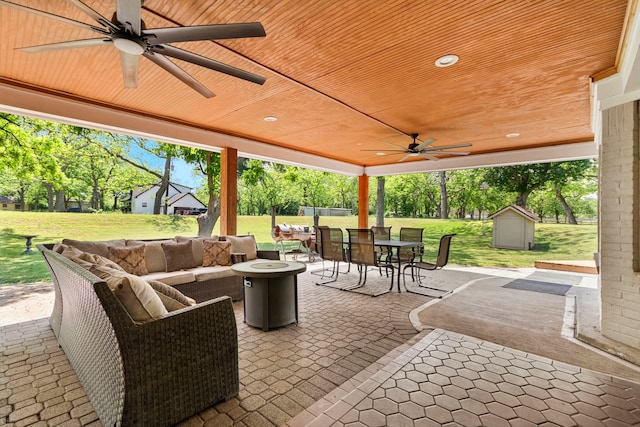 view of patio featuring ceiling fan, a storage shed, and an outdoor living space with a fire pit