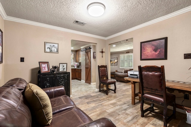 living room featuring crown molding, a barn door, a textured ceiling, and light wood-type flooring