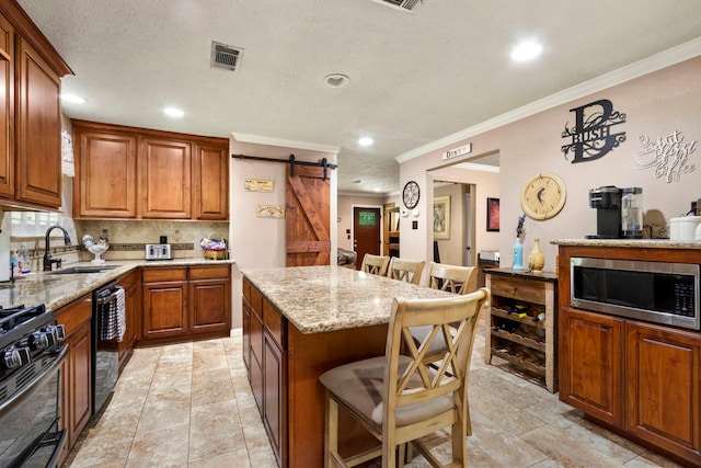 kitchen featuring a kitchen bar, sink, a center island, stainless steel microwave, and a barn door