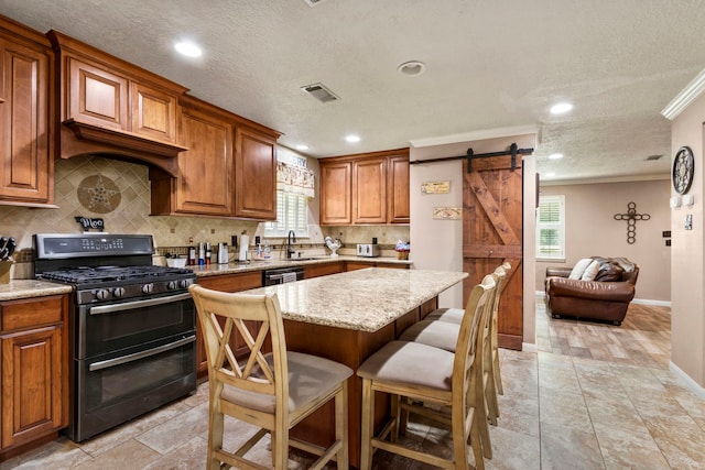 kitchen with a breakfast bar area, ornamental molding, a kitchen island, a barn door, and black appliances