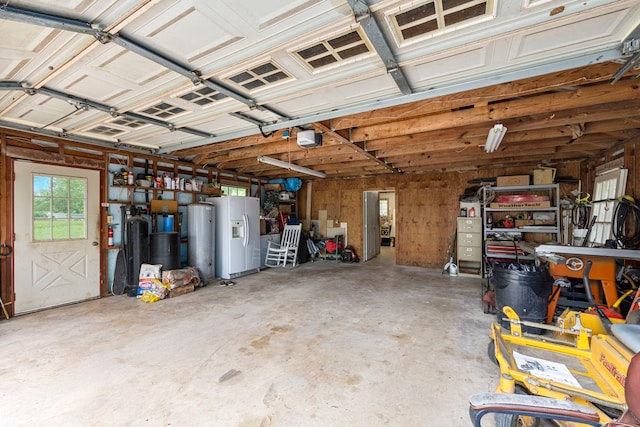 garage featuring a garage door opener and white refrigerator with ice dispenser