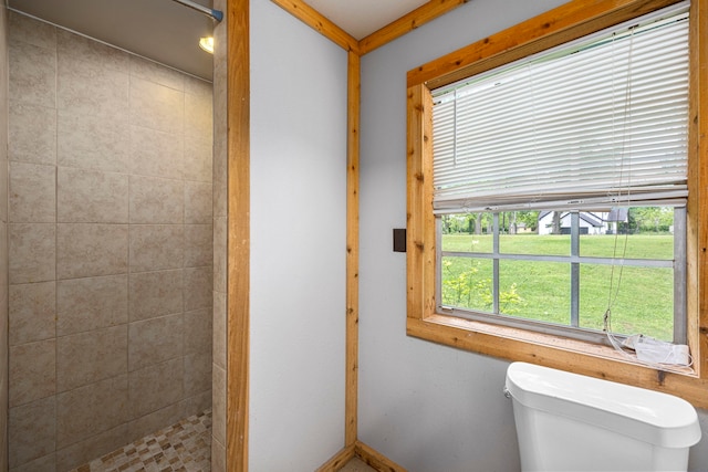 bathroom with a tile shower and toilet