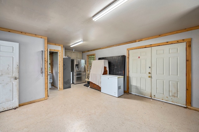 basement featuring stainless steel fridge with ice dispenser and refrigerator