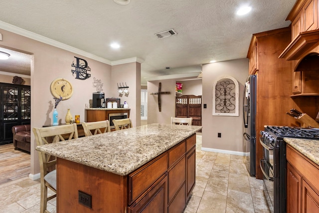 kitchen featuring light stone countertops, a center island, a breakfast bar, and black appliances