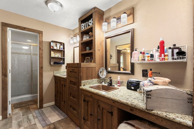 bathroom featuring vanity, a shower with shower door, and a textured ceiling